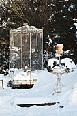 Verschneiter Vintage-Vogelkäfig im winterlichen Garten