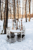 White garden table with candlesticks in a snowy forest