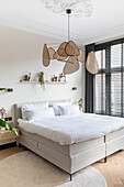 Modern bedroom with beige-colored double bed and decorative pendant light