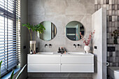 Modern bathroom with double sinks, round mirrors and partition wall