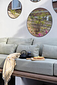 Garden lounge with light grey seating, round wall mirrors and tea service