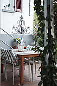 Tisch und Stühle mit maritimen Kissen, Leuchter und Rankpflanze auf der Terrasse