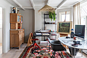 Room with workstations, carpet with floral pattern, easel and wooden kitchen hutch