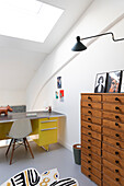 Work area in the attic with chest of drawers and desk, modern furnishings