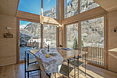 Dining area with wood paneling and panoramic windows in chalet