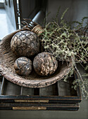 Decorative bowl with carved wooden baubles and dried twigs