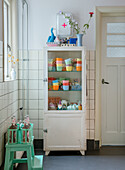 White vintage medicine cabinet with colourful cups in the kitchen