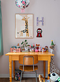 Children's workstation with colourful toys and giraffe picture on pink wall