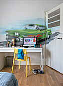 Jugendzimmer mit Auto-Wandmalerei, gelbem Stuhl und Laptopschreibtisch