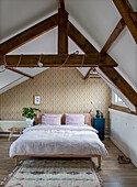 Attic bedroom with exposed beams and retro wallpaper