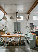 Dining room with wooden table, white chairs, mint green bench and fireplace