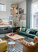 Modern living room with green sofa, rattan hanging lamps and striped carpet