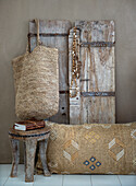 Rustic stool, decorative cushion and jewelry in front of wooden door