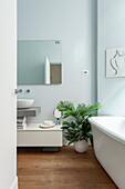 Minimalistisches, helles Badezimmer mit freistehender Badewanne und Grünpflanze