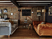 Living room with brick wall, two velvet sofas and wooden floor in rustic style