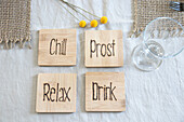 Vier Untersetzer aus Holz mit den Aufschriften "Chill", "Prost", "Relax" und "Drink"