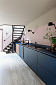 Modern kitchen with blue base units and staircase in the background