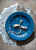 Blue ceramic plate with wooden cubes and snowdrops on a lace base