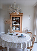 Round dining table with patterned tablecloth and crystal chandelier