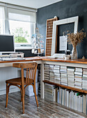 Study with wooden chair, stacks of books and black accent wall