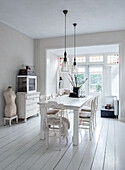 Country-style dining room with white wooden table and white chairs