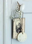 Picture frame with antique print and dried gypsophila flower on white doorknob