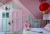 Bedroom with pink walls and integrated wardrobe under the sloping ceiling