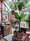 Living area with hanging plants under skylights and antique wooden console with washbasin