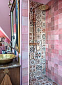 Shower with mosaic tiles and golden rain shower in pink tiled bathroom