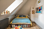 Attic room with patterned bed and integrated bookshelf