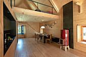 Loft with light wood panelling, dining area and red wood-burning stove as a colour accent, gallery sleeping area above