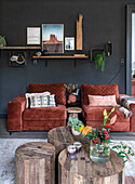 Cosy sitting area with red velvet armchairs and rustic wooden tables against a dark grey wall