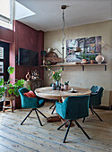 Modern dining room with round wooden table with blue velvet chairs with wooden floor and shelf