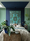 Bedroom with blue-green wall and hanging oriental carpet