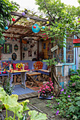 Cosy covered seating area in the garden with purple bench, colourful cushions and lanterns