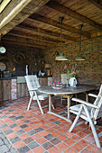 Covered patio area with wooden furniture and patterned tiles