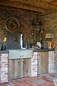 Rustic outdoor kitchen with stone sink and brick walls