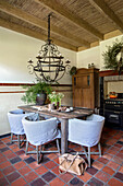 Dining room with rustic wooden table, light blue chairs, chandelier and tiled floor