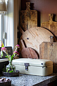 Vintage bread bin and chopping boards on kitchen counter in front of red-brown wall