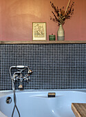 Bathtub with tiled mosaic and decoration on wall shelf