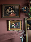 Gallery wall with classic paintings and mirror in front of red wall