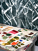 Artistic workspace with color samples, prints and leaf pattern wall