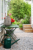 Grüner Klapptisch mit Vase und Gießkanne auf Kiesweg im Garten