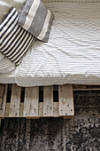 Bed with striped bed linen on pallets in the bedroom