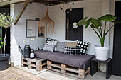 Cosy patio area with pallet sofa and large potted plants