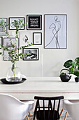 Modern dining area with white table, eucalyptus in glass vase and framed wall art