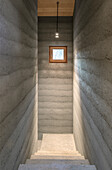 Minimalist concrete staircase with small window and pendant light