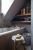 Bathroom with sloping roof, bathtub and wooden shelf