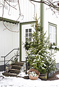 Snow-covered house entrance with fir tree and winter decorations