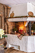 Decorated fireplace with candles, fir branches and fairy lights